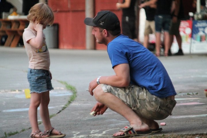 An adult crouching beside a child at the festival