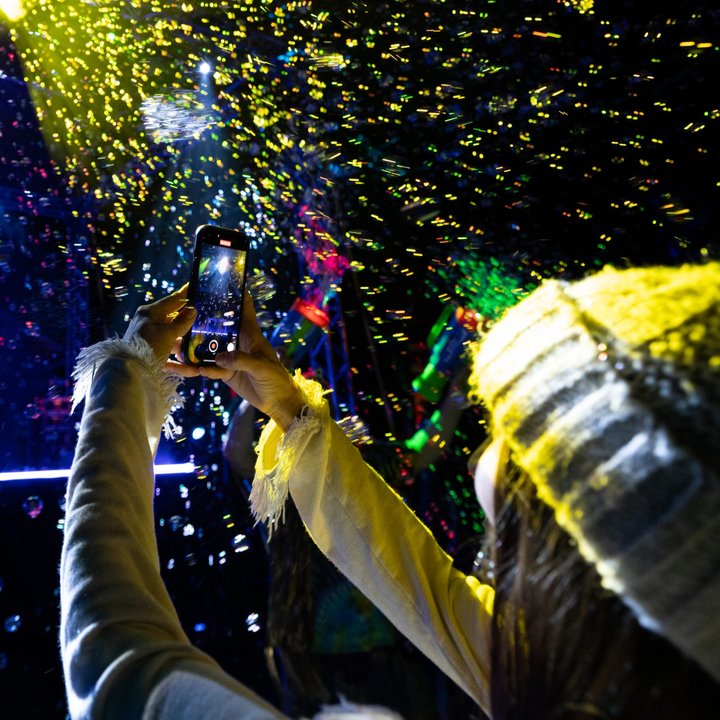 Festival attendee raising an arm beneath colorful lights