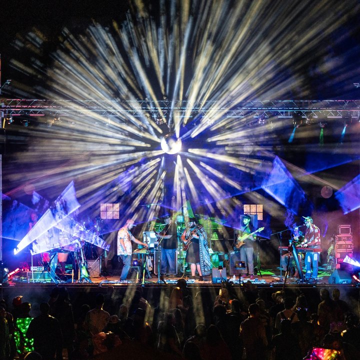 Nighttime band performance beneath radiating white and blue lights