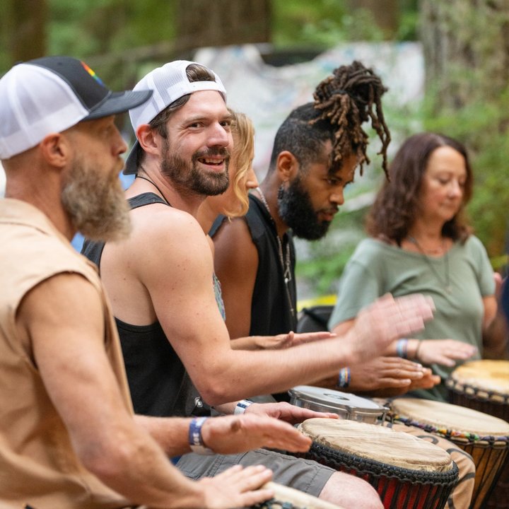 Festival musicians smiling while playing hand drums