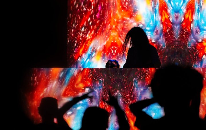 A DJ silhouetted against colorful stage projections