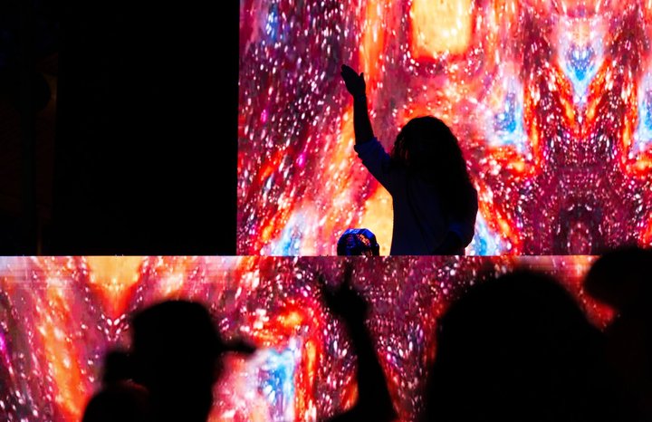 A performer raising an arm above a crowd at night