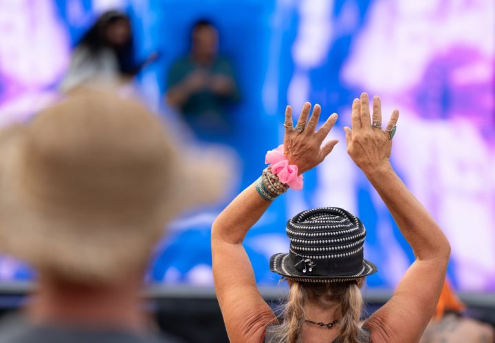 Festival attendee raising both hands in front of the stage